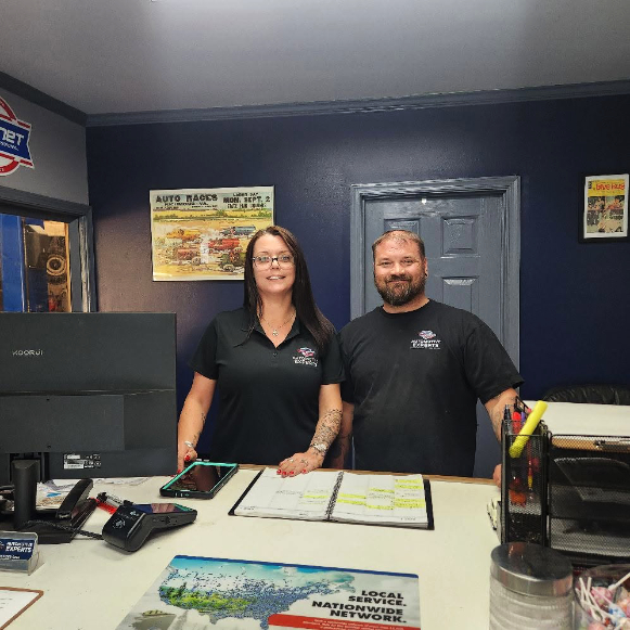 Couple standing behind the counter of an automotive repair shop.