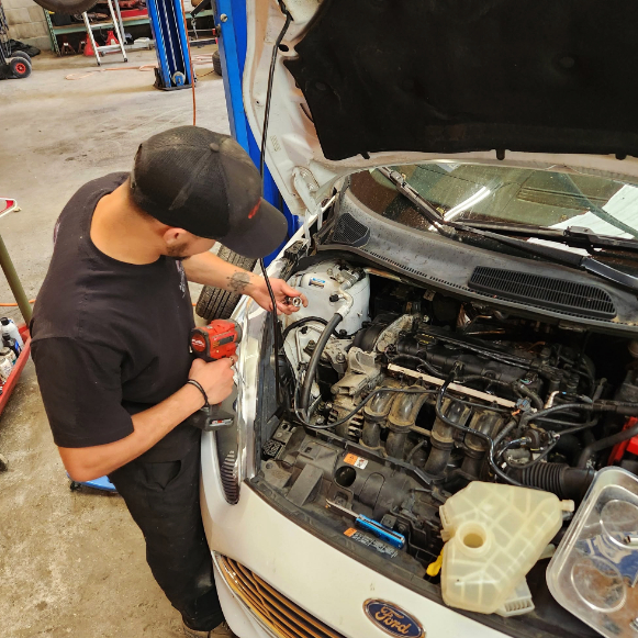 Mechanic performing routine maintenance on a Ford